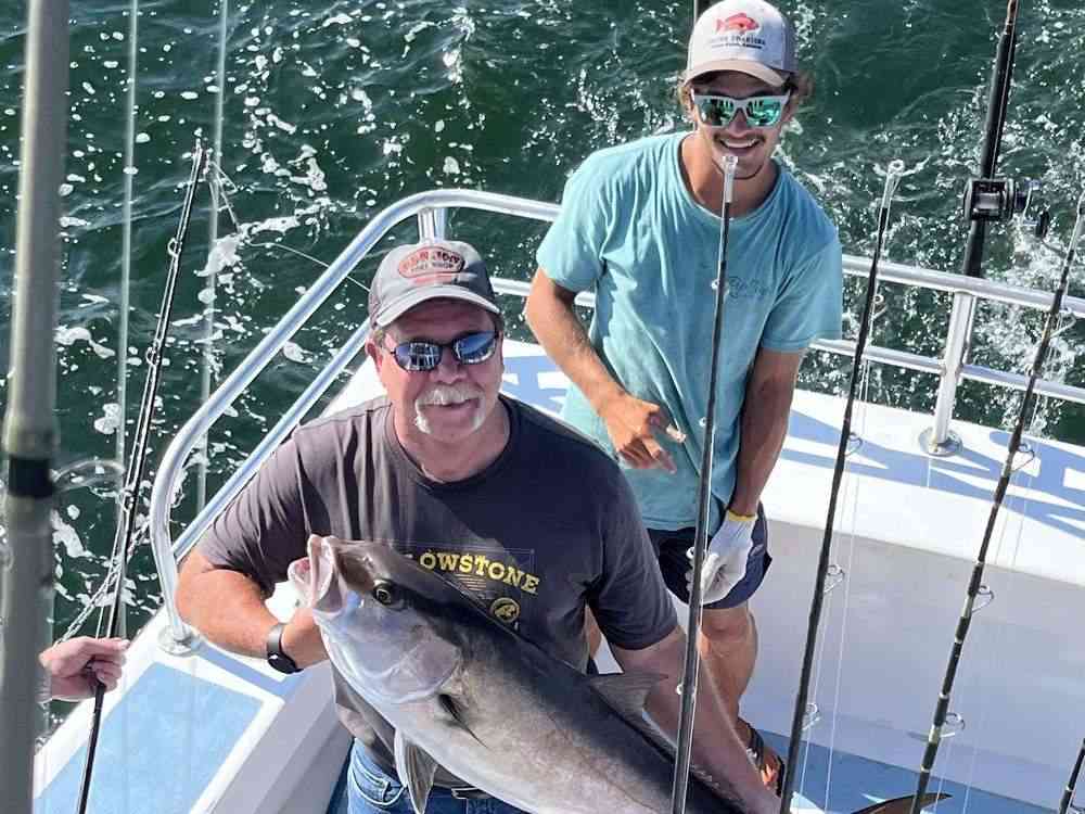 An angler holding a Gulf amberjack on the back deck