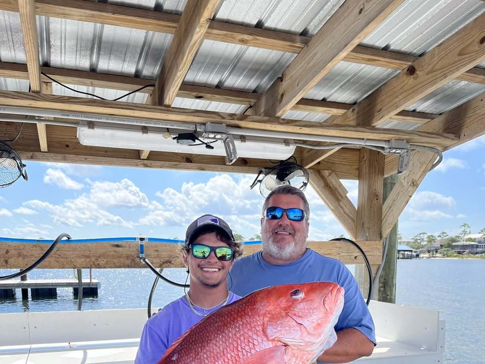 Two anglers with an oversized red snapper at the marina